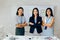 Smiling Asian young business women in casual wear standing in line with arms folded in meeting room