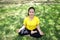 Smiling Asian young woman in yellow sportwear sitting and doing yoga for meditation for create concentration and calm the mind