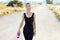 Smiling athletic woman walking on rural road and carrying water