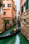 Smiling attractive Caucasian man and woman tourist couple riding in gondola. Gondolier navigating romantic tour in Venice, Italy