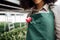 Smiling attractive darkskinned female gardener with flower on her workplace