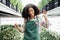 Smiling attractive darkskinned female gardener with flower on her workplace