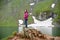 Smiling attractive female posing on rock near green rocky mountains close to artificial Vidraru lake in Romania