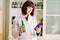 Smiling attractive young lady pharmacist holding green and blue glass bottles in her hands on the background of pharmacy