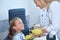 Smiling audiologist with a medical device leaning towards a patient