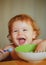 Smiling baby eating food. Cutr baby child eating himself with a spoon. Launching child eating food.