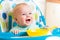Smiling baby eating food on kitchen