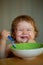 Smiling baby eating food. Launching child with spoon.