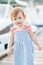 Smiling baby girl 1-2 year old wear striped dress and holding walk over wooden pier at sea shore outdoors.