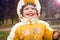 Smiling baby in nature in warm clothes in early spring. Joyful child in hood outdoors. Portrait of child with happy smile.