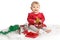 Smiling baby in red velvet dress and holiday gifts