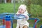 Smiling baby toddler rides carousel in playground outside. Concept of kindergarten and childhood