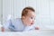 Smiling baby tummy time in a white nursery