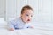 Smiling baby tummy time in a white nursery