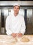 Smiling baker kneading dough in bakery