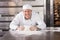 Smiling baker kneading dough on counter