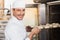 Smiling baker putting dough in oven