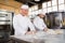 Smiling bakers kneading dough at counter