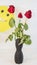 A smiling balloon on a background of old roses.Three wilted roses in a vase on the table with a yellow balloon with a smile. Old