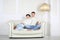 Smiling barefoot husband and wife sits on white sofa