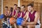 Smiling basketball players sitting on bench with basketball in the court