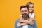 Smiling bearded man in casual clothes have fun with cute child baby girl. Father little kid daughter isolated on yellow