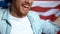 Smiling bearded man holding American flag, supporting candidate, elections