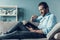 Smiling Bearded Man Reading Book on Gray Sofa.