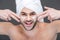 smiling bearded man in towel applying face cream,