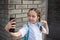 Smiling beatiful preteen girl taking a selfie outdoors. Child taking a self portrait with mobile phone. technology