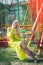 Smiling beautiful blonde fashion woman in long elegant yellow dress sit on flying carousel in high heel sandals summer