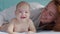 Smiling beautiful Caucasian mother playing with newborn baby boy on the bed in bedroom. Parent and cute infant childhood