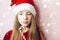 Smiling beautiful girl with long hair in fluffy Santa Claus hat on a pink background