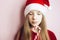 Smiling beautiful girl with long hair in fluffy Santa Claus hat on a pink background.