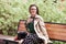 Smiling beautiful girl siting in a city park on a bench . Wind developing long hair of happy young woman. Copy space