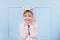 Smiling beautiful little girl in unicorn pink costume is smiling and having fun on a blue wall background. happy childhood