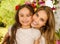 Smiling beautiful mom hugging her pretty daugher in beige dress wearing two red ties in hair