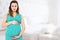 Smiling beautiful pregnant woman at home with big belly. Pregnancy and motherhood concept. Happy baby expectation. Copy space