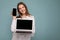 Smiling Beautiful satisfied happy young woman holding computer laptop and mobile phone looking at camera wearing shirt