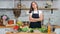 Smiling beautiful vegan female in apron posing at kitchen surrounded by fresh vegetable and fruit