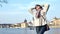 Smiling beautiful woman posing on embankment with view on historical building and water transport