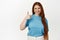 Smiling beautiful woman with red hair, ginger girl shows thumb up in approval, support and agree, praise nice choice