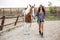 Smiling beautiful young woman cowgirl walking with horse