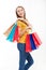 Smiling beautiful young woman holding shopping bags and casual style on white background. Jeans and yellow shirt.