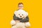 Smiling bespectacled brunet boy holds large teddy bear toy looking into the camera. Copy space, mock up