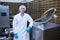 Smiling biologist leaning against storage tank