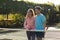 Smiling biracial couple playing tennis embracing on sunny outdoor tennis court