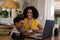 Smiling biracial mother looking at son studying online over laptop at home