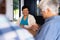 Smiling biracial senior woman talking with male friend while sitting at dining table in nursing home