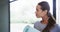 Smiling biracial young woman holding mat while standing against window in yoga studio